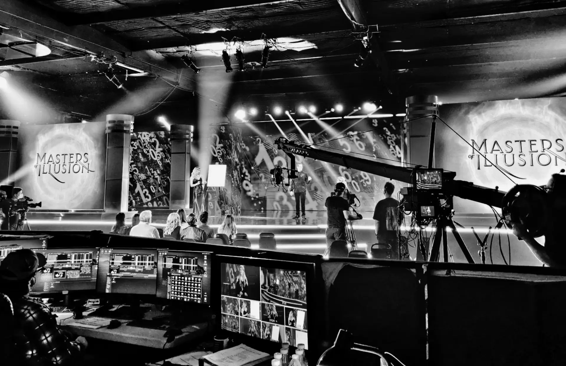 A live television stage set lit by beams, with cameras and a control desk