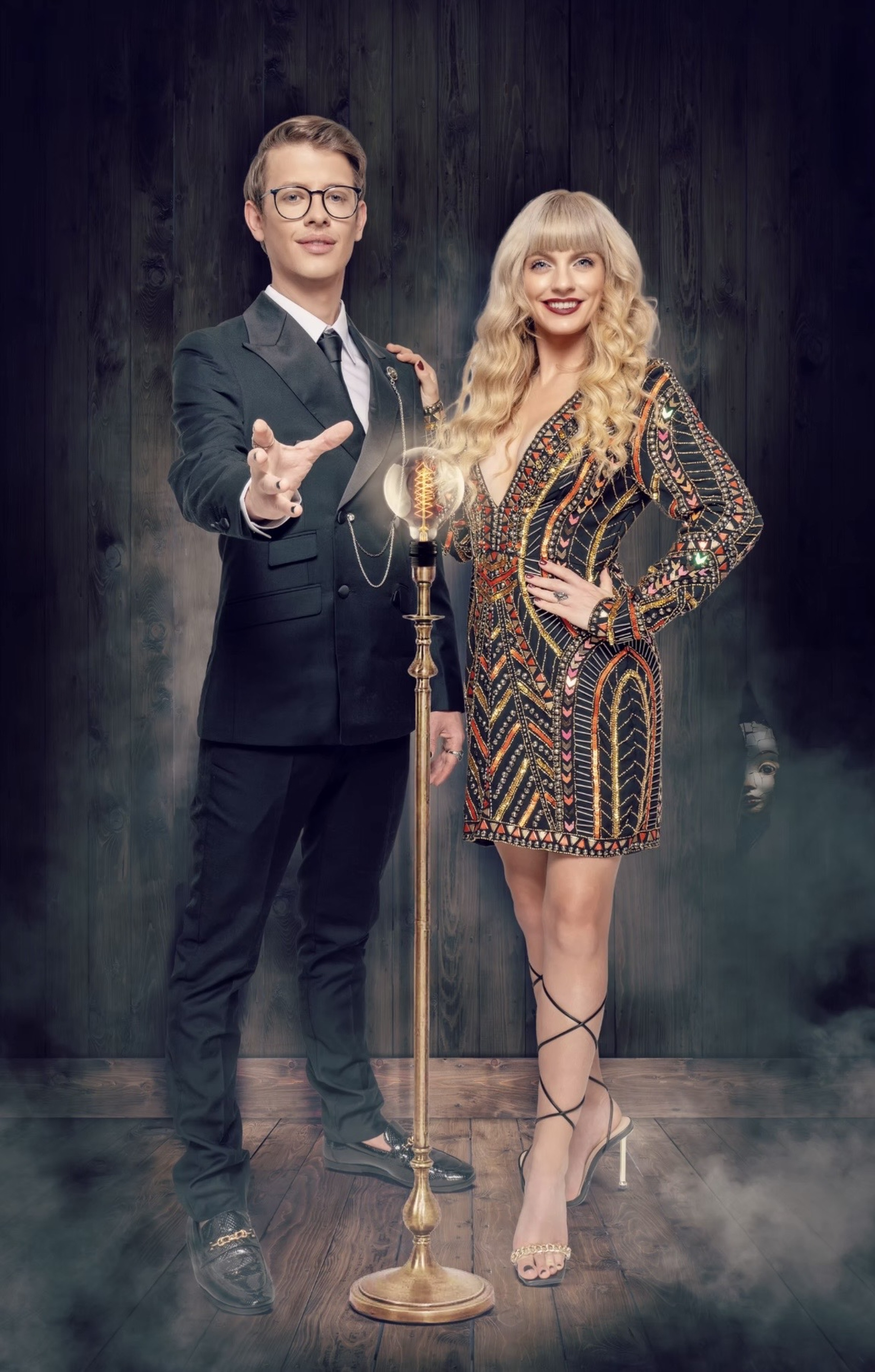 Matthew Pomeroy and Natasha Lamb standing beside a lit antique lamp on a smoky stage