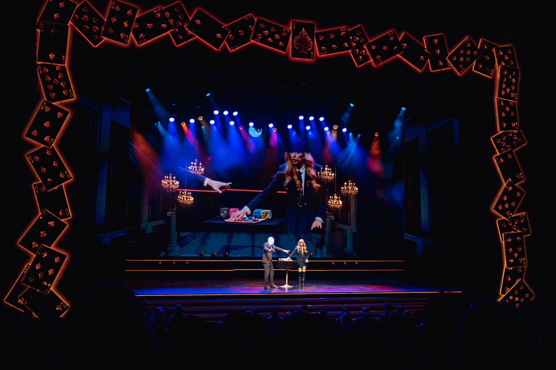 The Conjurors on stage inside a frame of glowing playing cards