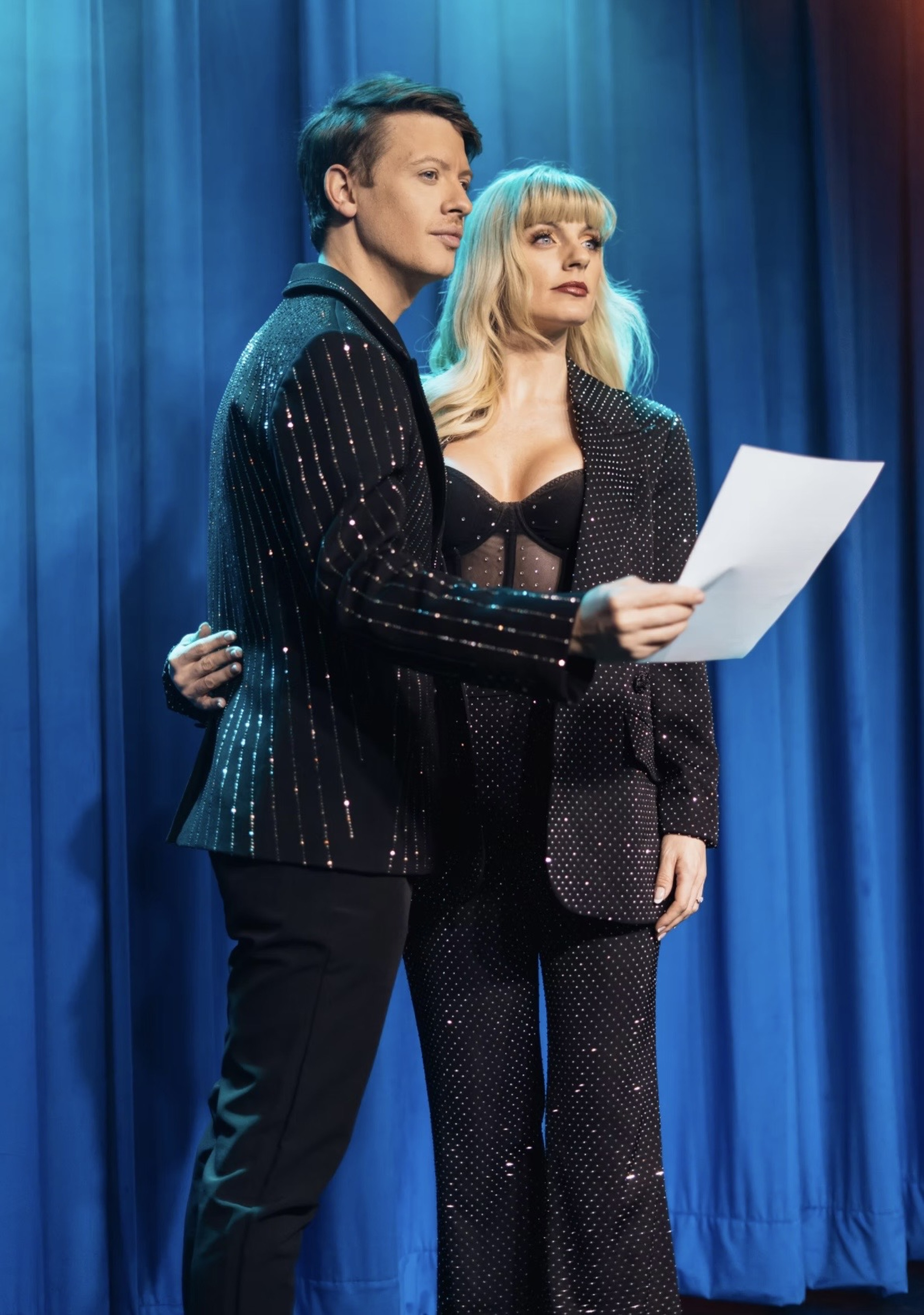 Matthew Pomeroy and Natasha Lamb reading together beside a blue stage curtain