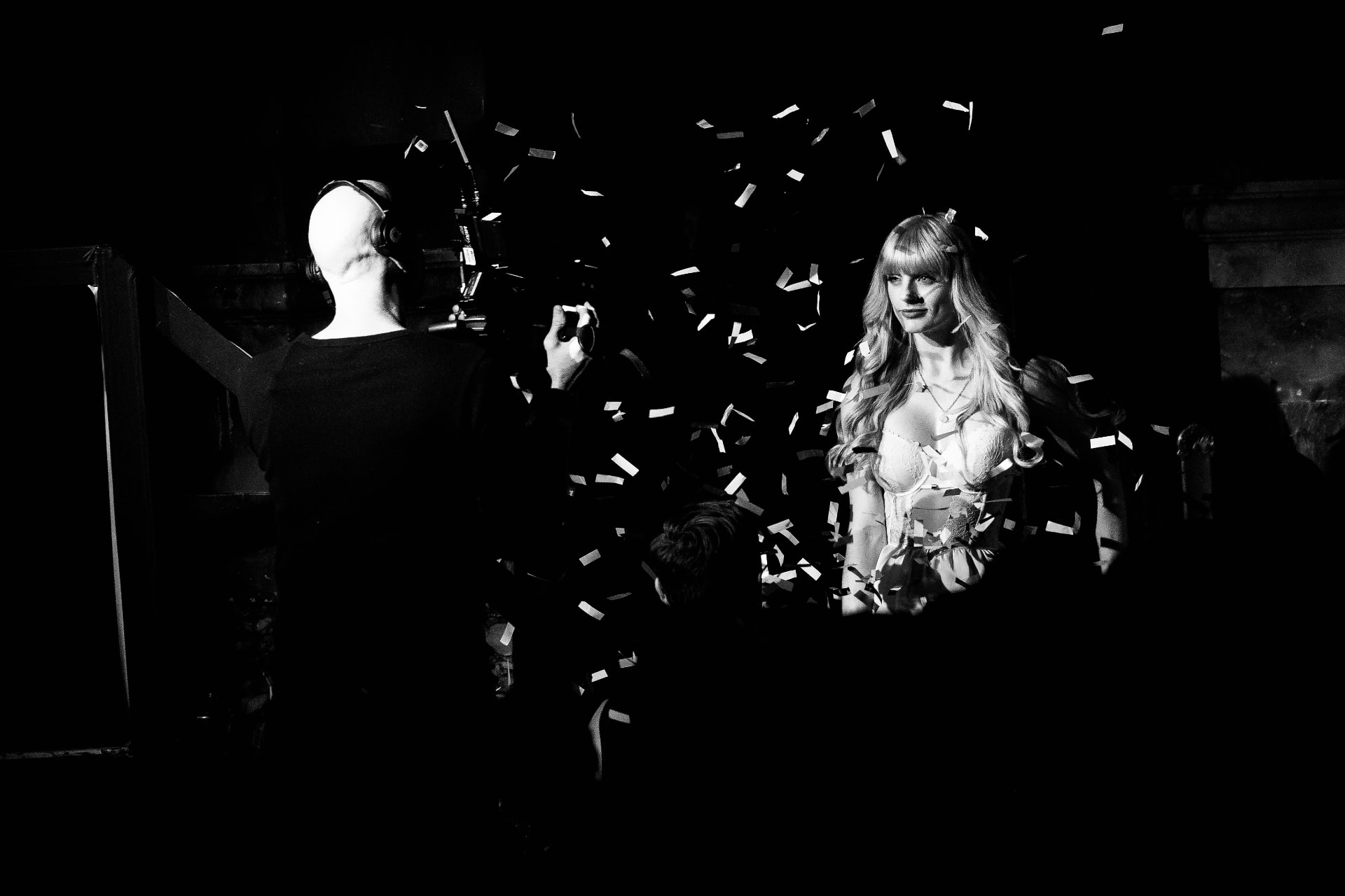 Natasha standing in falling confetti beside a camera operator