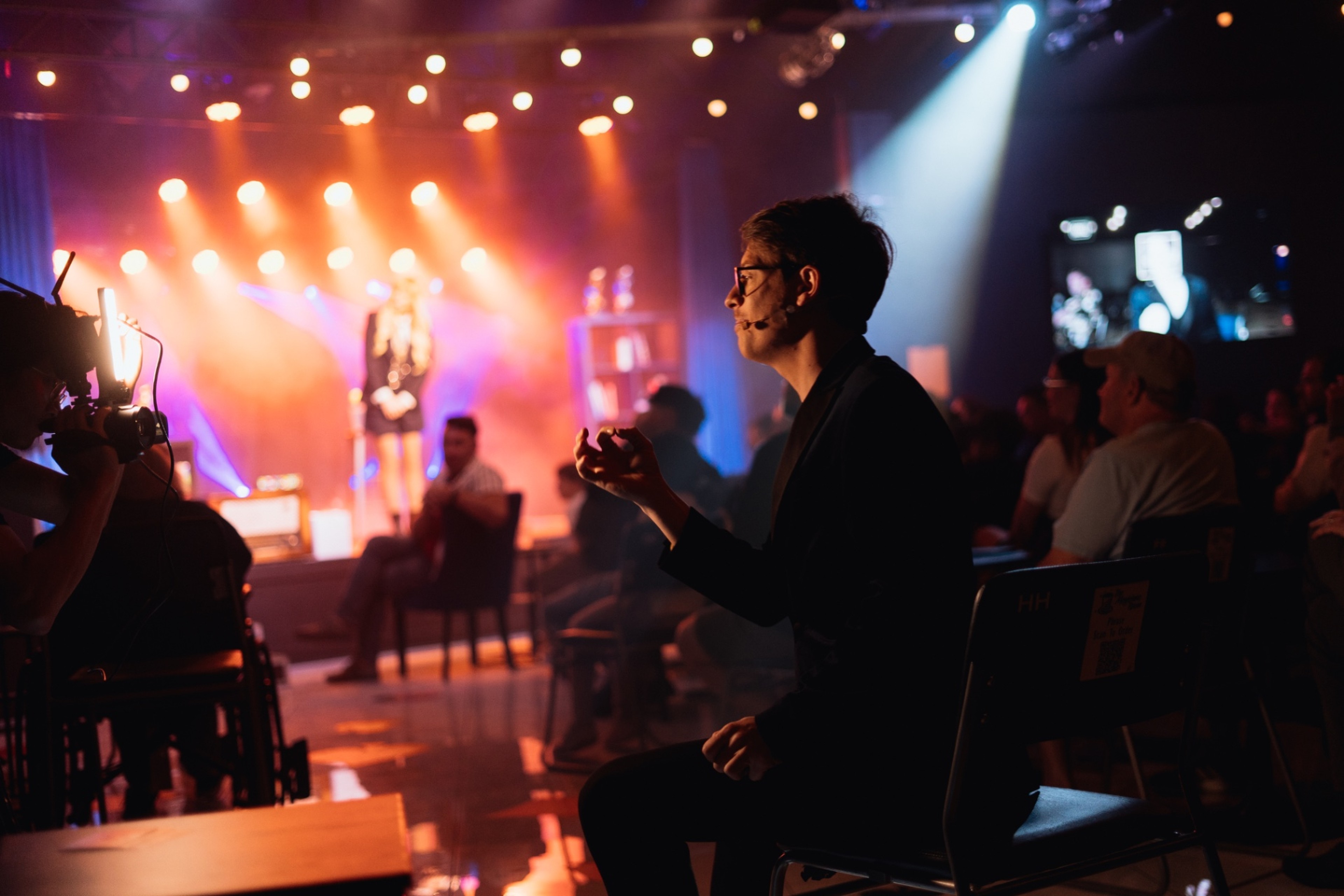 Matthew Pomeroy performing seated among the audience under warm stage light